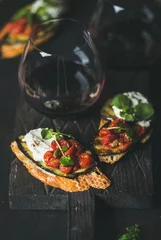  Wine and snack set. Brushetta with roasted eggplant, tomatoes, garlic, cream cheese, arugula and glass of red wine on wooden board over dark background, selective focus. Slow food, party food concept © sonyakamoz