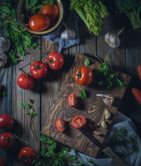 fresh tomatoes with herbs, cabbage, garlic and carrot on a wooden desk and on a wooden table, slightly toned