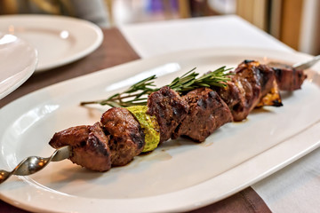 Beef kebab with vegetables and rosemary seasoning on a white plate