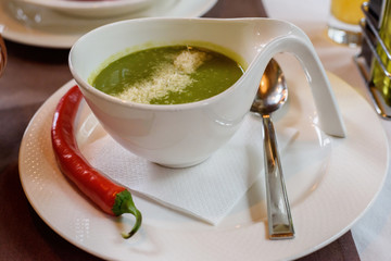 Spinach cream soup with chili in a white bowl