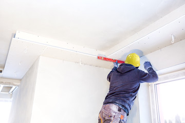 Workers assemble a suspended ceiling with drywall