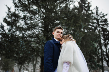 Stylish wedding couple at winter day background pinewood.