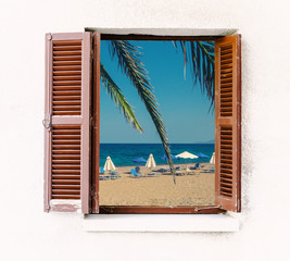 Open window of the old house with brown wooden shutters and seaside view. Summer beach - look out through the window frame for your idea of sea vacation. Window with retro blinds in colonial style.