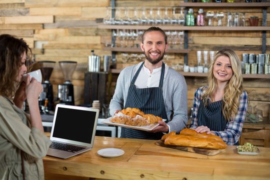 Woman using laptop and waiter and waitress working at counter