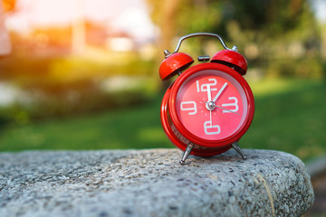 Alarm clock on bench with blurred background.