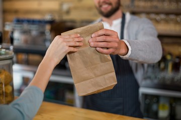 Woman receiving parcel from waiter at counter