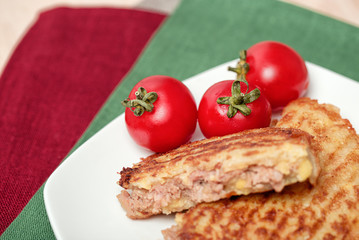 Fried potatoes with small red tomatoes on a green background