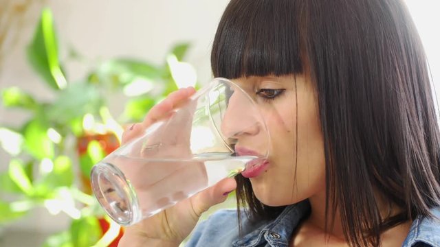 pretty young brunette woman drinks a glass of water