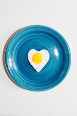 heart egg in a blue plate- white background, minimal love food theme concept
