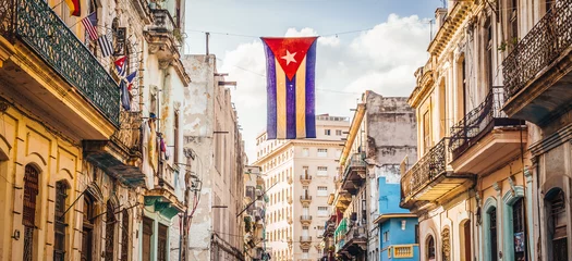 Fotobehang Havana Een Cubaanse vlag met gaten zwaait over een straat in Centraal Havana. La Habana, zoals de lokale bevolking het noemt, is de hoofdstad van Cuba