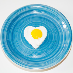 heart egg in a blue plate- white background, minimal love food theme concept