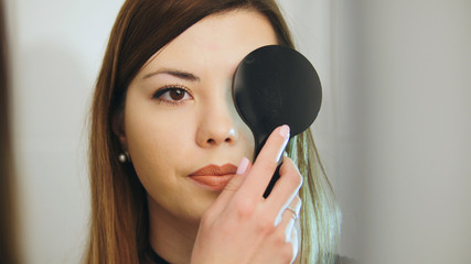 Ophthalmology medical, health, concept - beautiful girl checks vision in an ophthalmologist with one eye closed © KONSTANTIN SHISHKIN