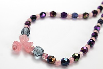 Handmade DIY colorful necklace from jewelry wire and glass beads, pink glass flower as pendant