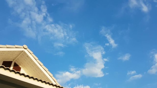 time lapse clouds in the sky with foreground of house roof 