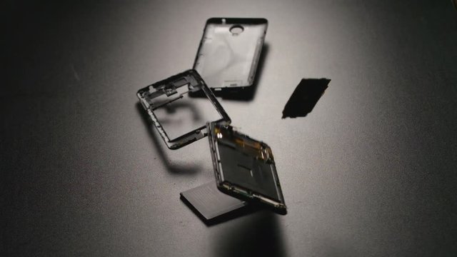 SLOW MOTION: Smartphone falls on a floor, breaks and a parts fly away