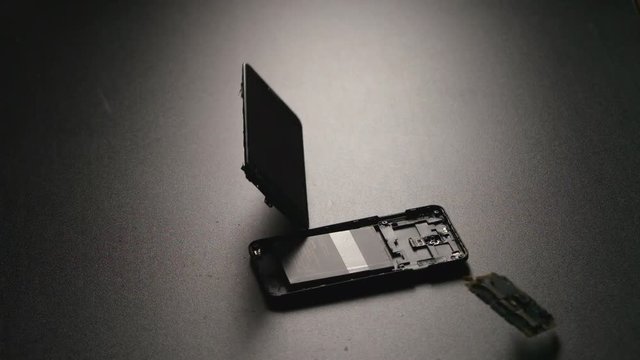 SLOW MOTION: Smartphone falls on a floor and breaks on a parts in center