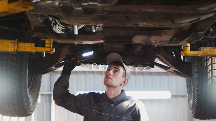 Car service - a mechanic checks the suspension of SUV