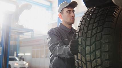Fototapeta na wymiar Car service - a mechanic checks the wheel of SUV, wide angle