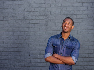 smiling african man standing against gray wall looking up