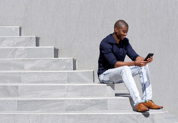 young african american man sitting on steps using tablet - Powered by Adobe
