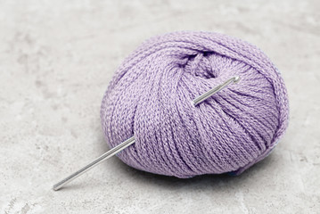 crochet hook with a  violet ball of wool yarn