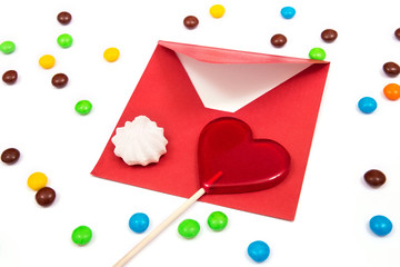Gift for Valentines day. Red envelope, meringue, and red lollipop in the shape of a heart on the...