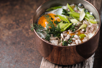 Scrambled eggs  with greens in the copper pot on the metal table  horizontal