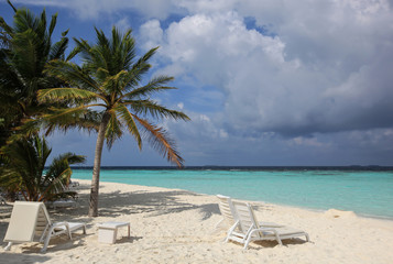 Fototapeta na wymiar Plastic sunbeds and table on the tropical beach, Maldives