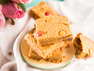 Festive breakfast set pastel color tray. Flowers roses Valentine's Mother day home made baked treat with candies. Peanut butter blonde bownies.