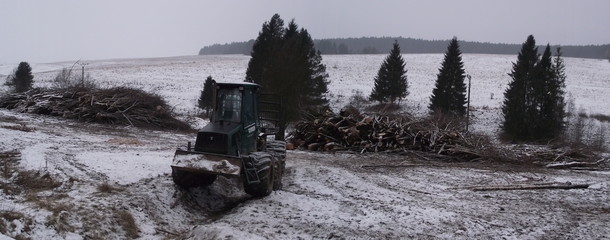 Working tractor in winter forest