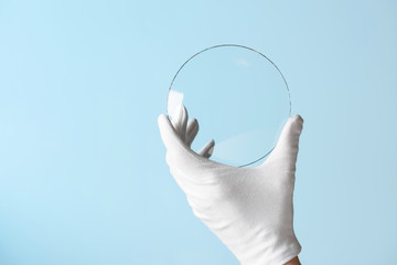 Scientist hand in glove show circle piece of new research prototype of transparent clear glass or...