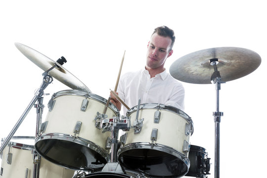 drummer behind drum set wears white shirt and plays the drums