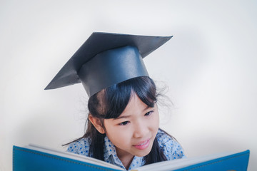  Asian school kid graduate in graduation cap and reading a book