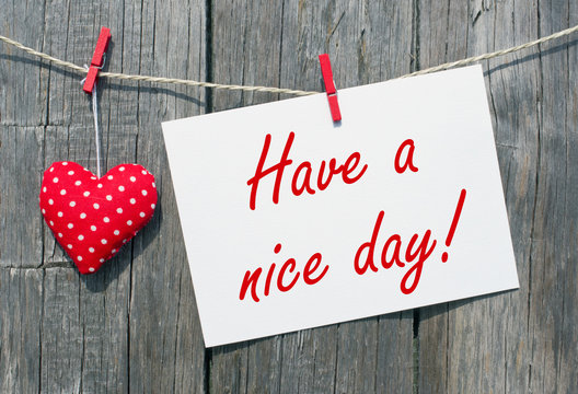 Have a nice day - red heart with postcard and text on wooden background