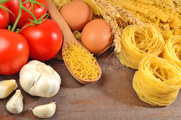 Uncooked Italian pasta, ripe tomatoes branch, garlic and eggs