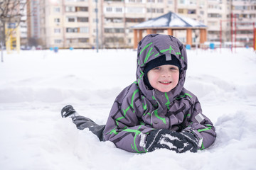 Fototapeta na wymiar Cute little kid boy in colorful winter clothes making snow angel, laying down on . Active outdoors leisure with children in . Happy child.
