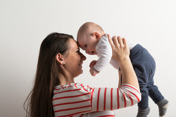 Beautiful mother holding baby son in her arms. Studio shot.