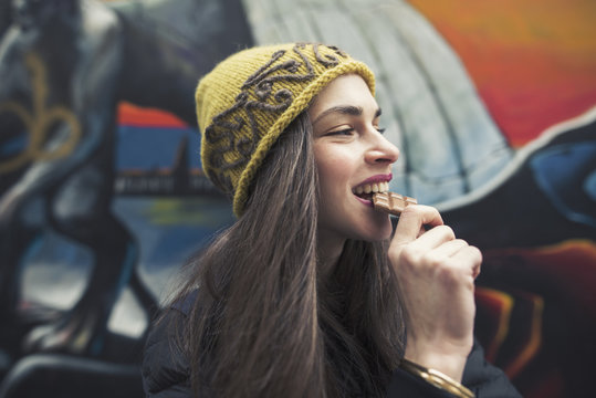 candid image of a beautiful young woman biting a chocolate bar
