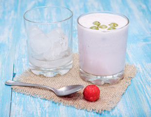 Milkshake with strawberries, gooseberries and ice on a blue table.