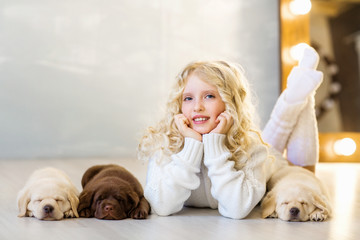 Little girl with a labrador puppies