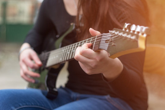 Close up female musician hands playing electric guitar. Lens fla