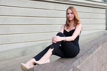 Young beautiful fashion woman  sitting on the gray plaster walls