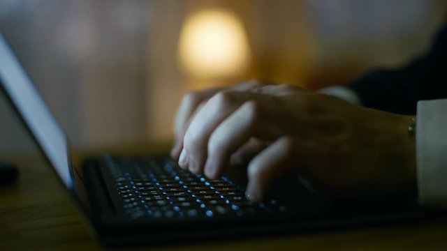 Close-up of Man's Hands Typing on a Laptop. In the Background Warm and Homely Atmosphere. Shot on RED EPIC-W 8K Helium Cinema Camera.