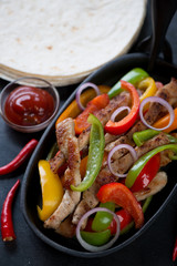 Close-up of a cast-iron frying pan with mexican pork fajitas