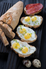 Close-up of bruschettas with fried quail eggs, studio shot