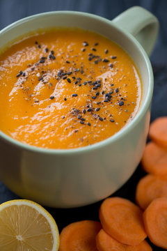 Closeup of olive-colored cup with carrot cream-soup, studio shot
