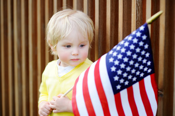 Cute toddler boy holding american flag