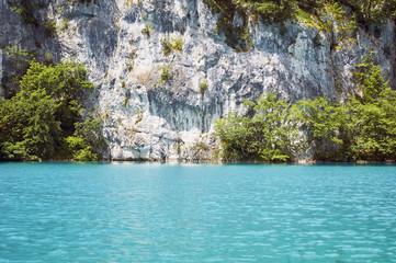 Fototapeta na wymiar Plitvice Lakes in Croatia Beautiful lake with azure water and waterfalls surrounded by greenery and a rock wall, summer vacation