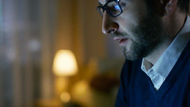 Close-up of a Middle Aged Man Working on a Laptop. He's at Home Alone. Computer's Screen Reflects in His Glasses. Shot on RED EPIC-W 8K Helium Cinema Camera.