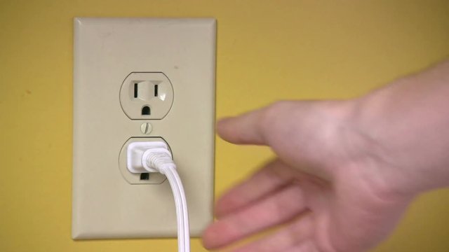 An electrical wall outlet is plugged in and unplugged.  This was filmed in America.
